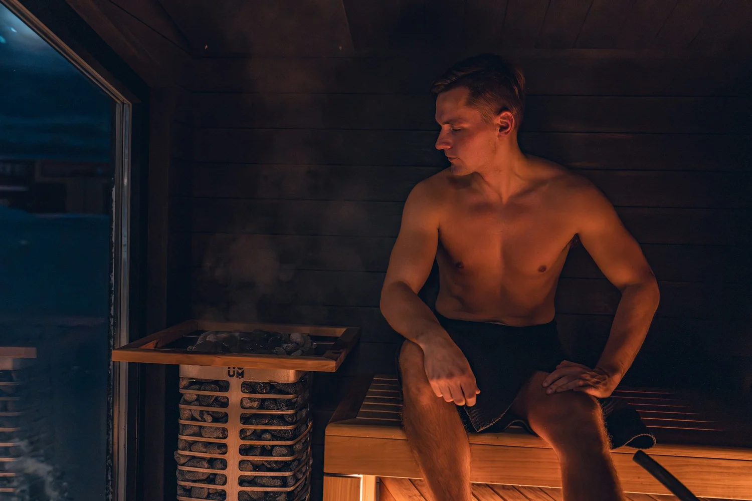 Warm cedar sauna interior with bench seating and lake light