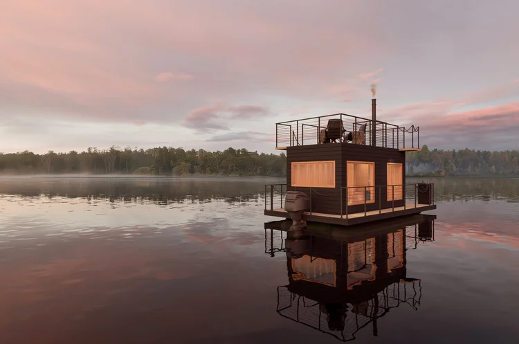The Cedar Room floating sauna glowing on calm sunset water